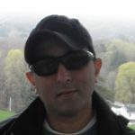 Headshot of Joel Isaac. He has a light skin tone and is wearing black sunglasses, a black cap, and black jacket.
